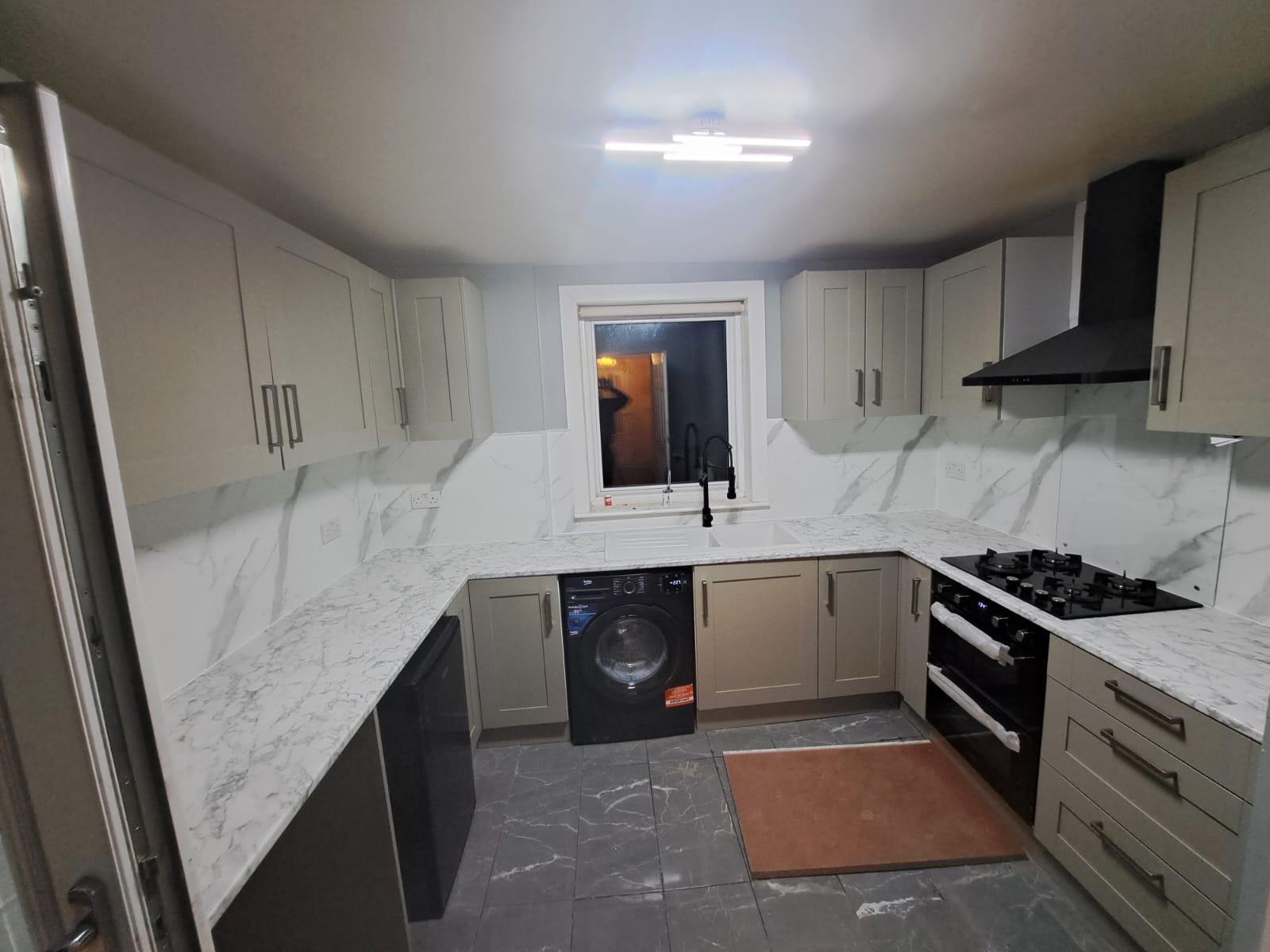 Fitted grey kitchen with marble-effect worktops, oven, hob and washing machine